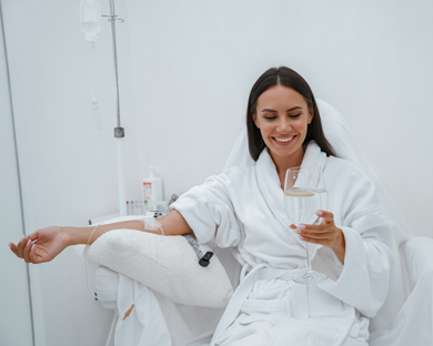 woman enjoying glass of water whilst having iv drip therapy