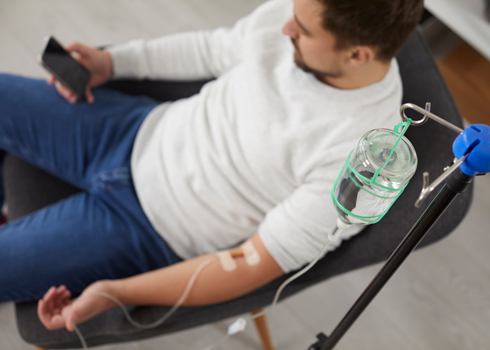 man having iv drip therapy, relaxed on phone