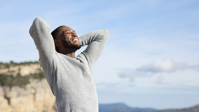 man cheerfully looking up to sky with arms behind head