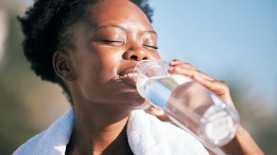 content woman after workout concept, drinking water from glass bottle