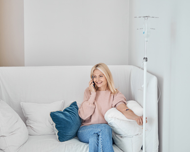 woman sat on sofa having iv drip therapy