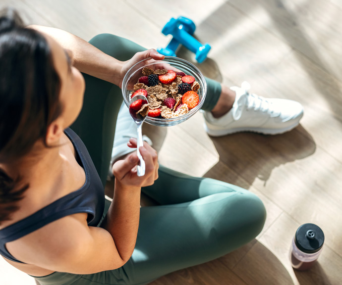 woman on floor eating cereal after workout concept