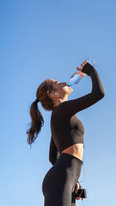 after workout concept, woman in black long sleeve workout gear drinking water from bottle